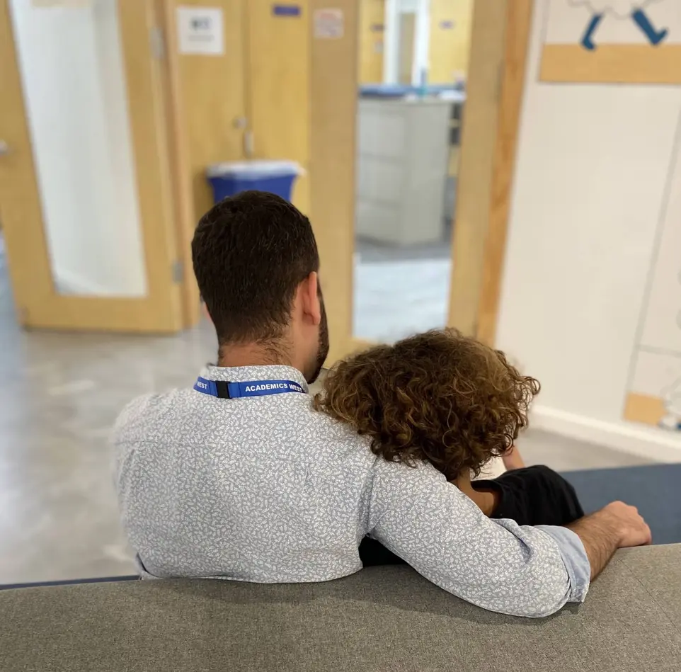 A man and a child collaborate on a couch in an office at Academics West high-support school.