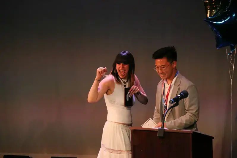 A man and woman stand at a podium decorated with colorful balloons, representing Academics West programs and affiliations.