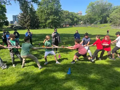 A group of children enthusiastically playing tug of war in a sunny park, showcasing teamwork and outdoor fun.
