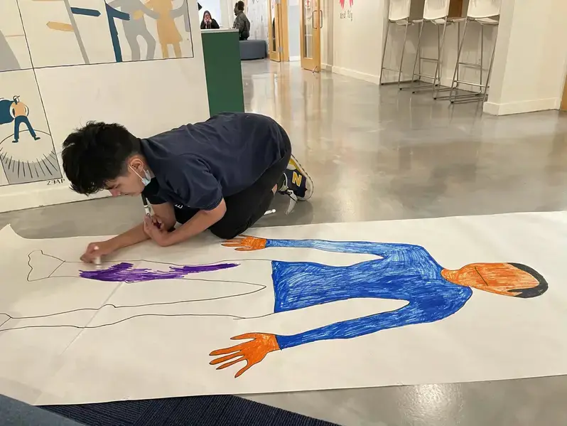 A young boy engaged in drawing on a large sheet of paper during a supportive counseling session.