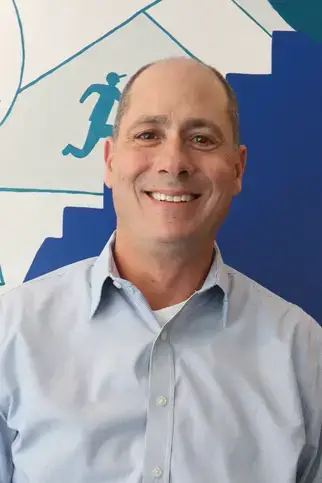 Evan Flamenbaum, MA, DSW, smiling in a blue shirt, posed for a faculty portrait.