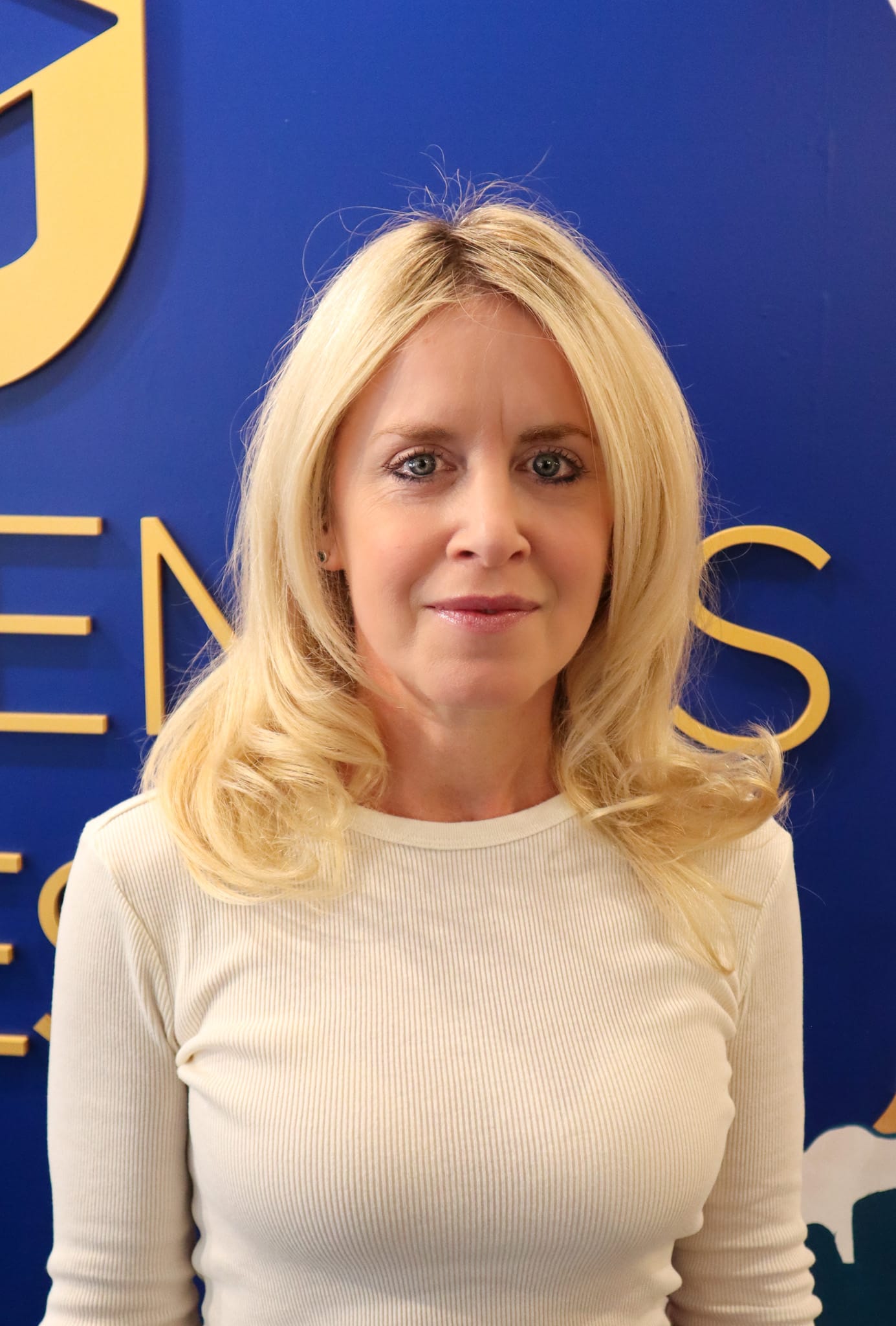 Thea Cruz, M.S., CCC-SLP, Assistant Head of School, wearing a blue shirt and blue jacket, smiling for her faculty portrait.